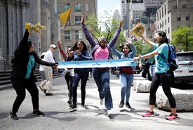 NYRR staff holding up a finish line for runners in a park on Global Running Day