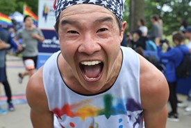 An NYRR staffer wearing a November Project singlet cheering at a race. 