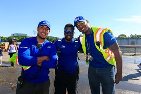 Three NYRR staffers at a race, smiling at the camera. 