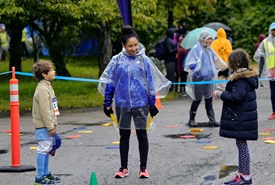 A NYRR staffer talking to two kids at an event. 