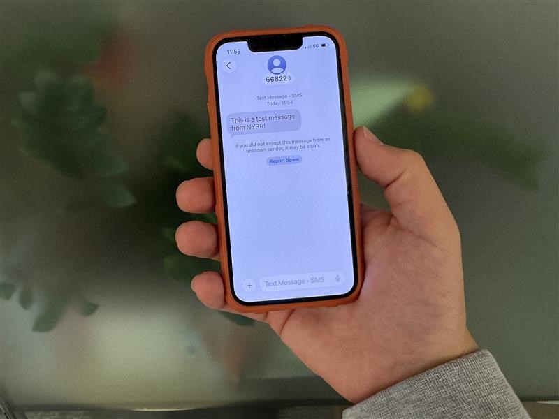 a hand holding a cell phone with a text on its screen that reads