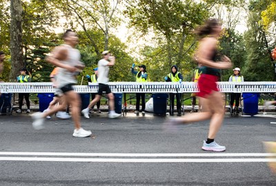 Runners running past a water station with volunteers handing out cups of water