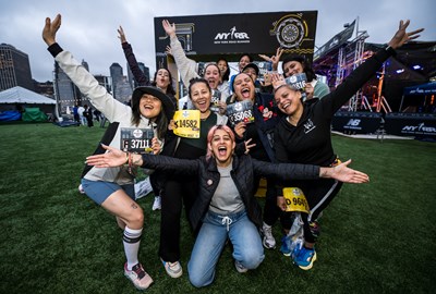 A group shot of runners with their arms outstretched and bibs in hand at the RBC Brooklyn Half Pre-Party