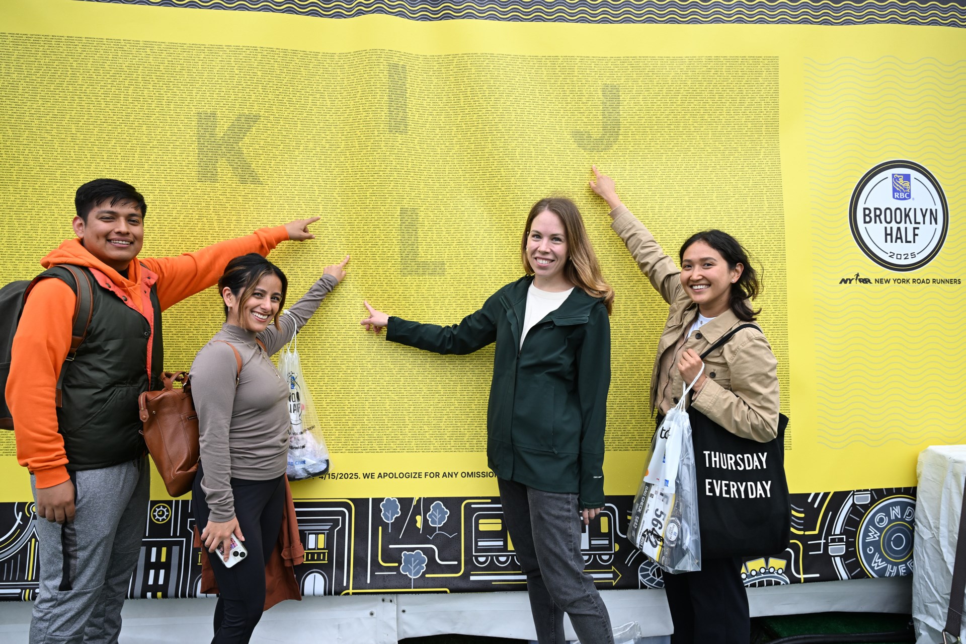 Runners point to their names on the name wall at the 2025 RBC Brooklyn Half Pre-Party