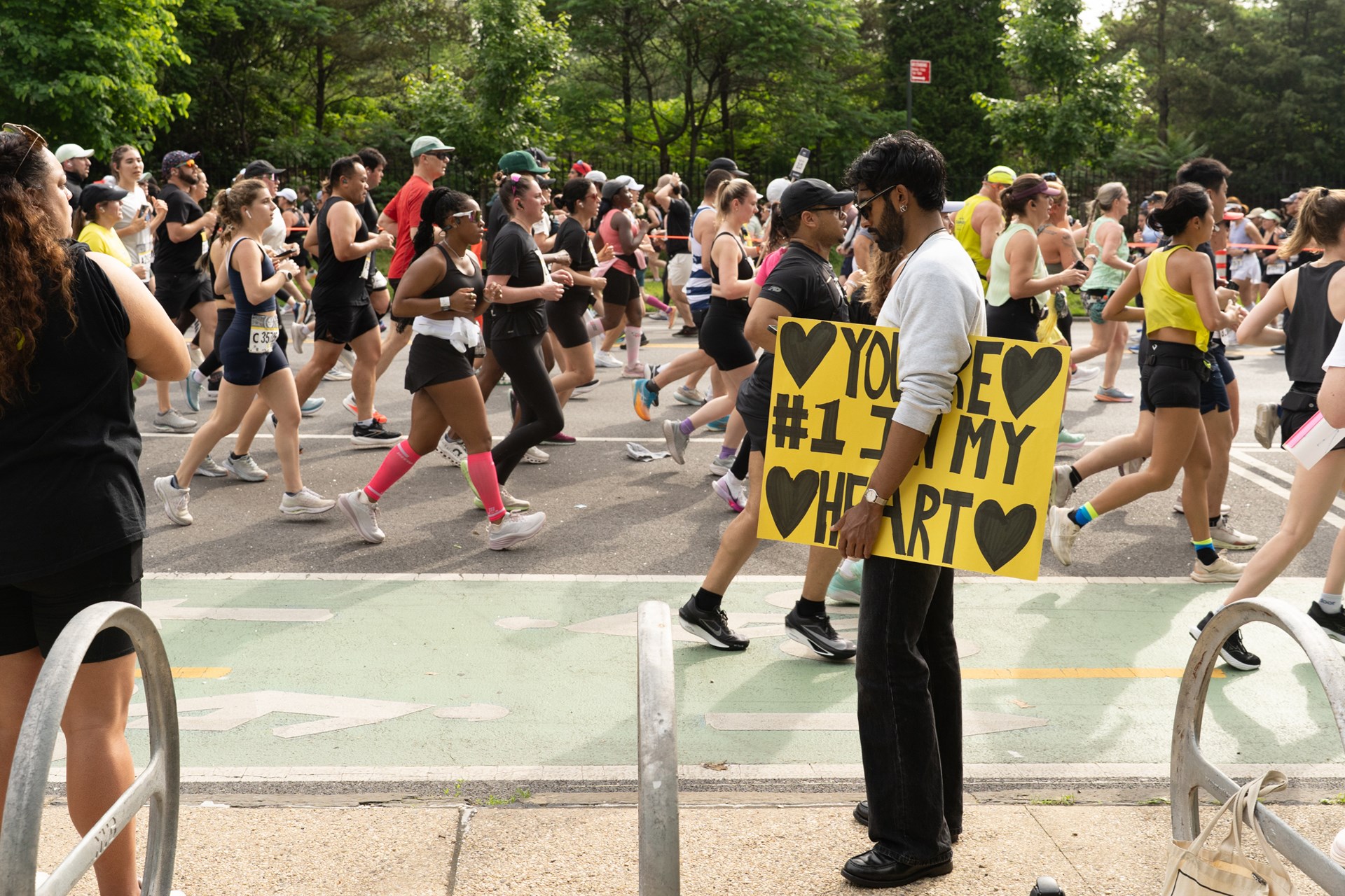Runners at the RBC Brooklyn Half alongside a spectator with a sign that reads, "You're #1 in my heart"