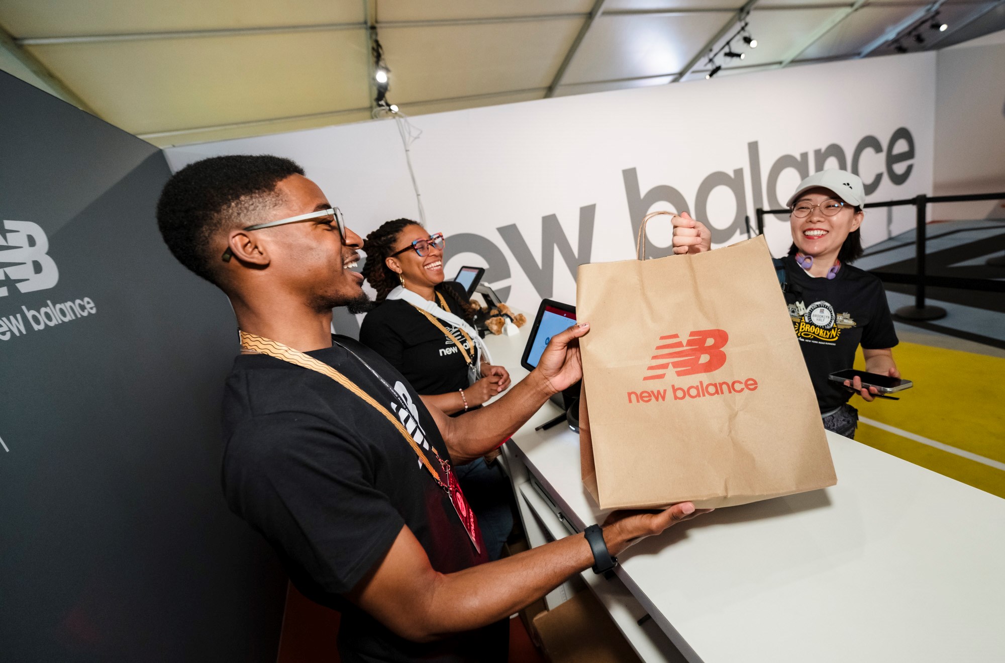 A woman is being handed a New Balance shopping bag at the New Balance store at the 2025 RBC Brooklyn Half Pre-Party