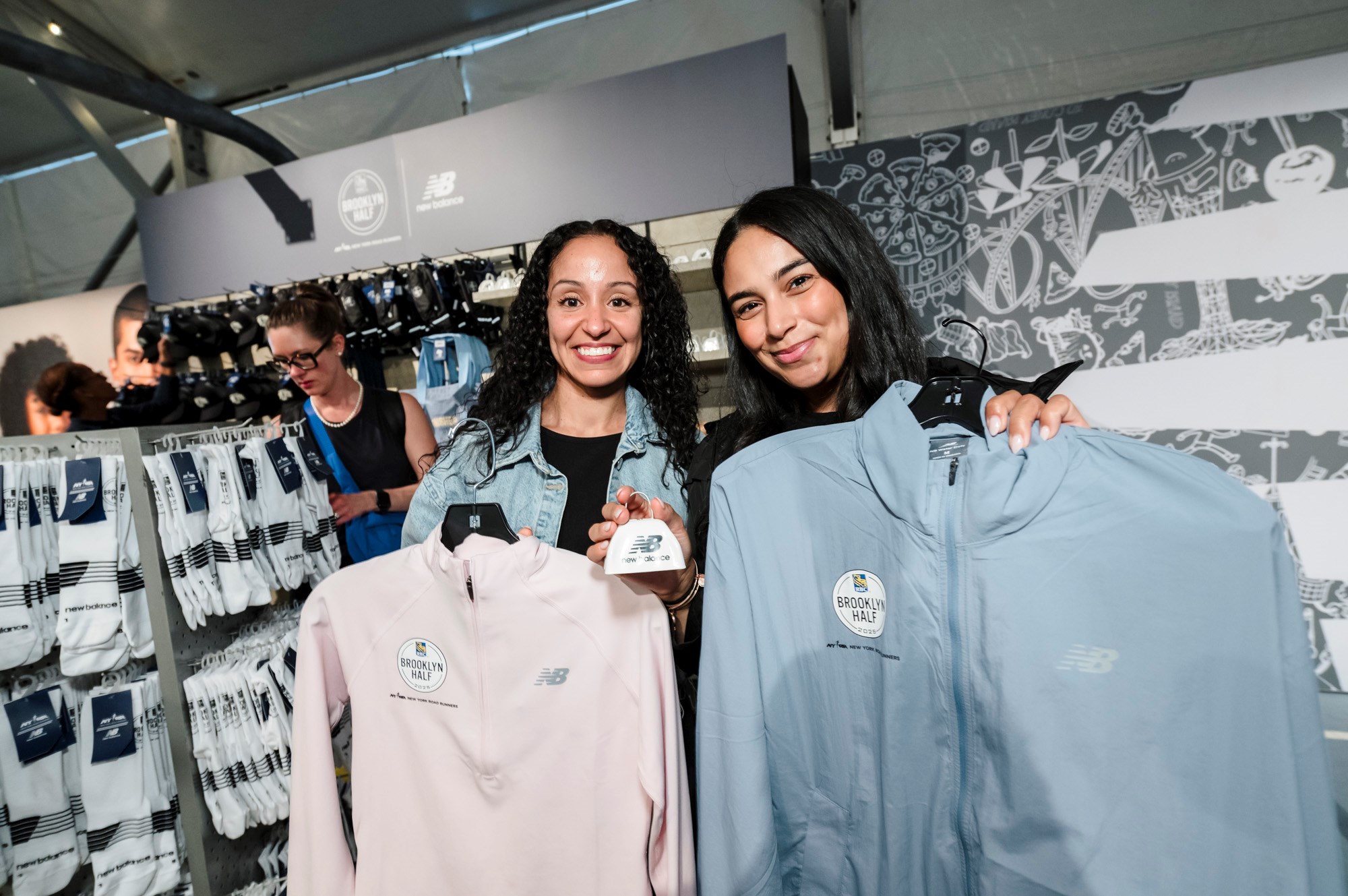 Two women pose for a photo with New Balance clothes in the New Balance store at the 2025 RBC Brooklyn Half Pre-Party