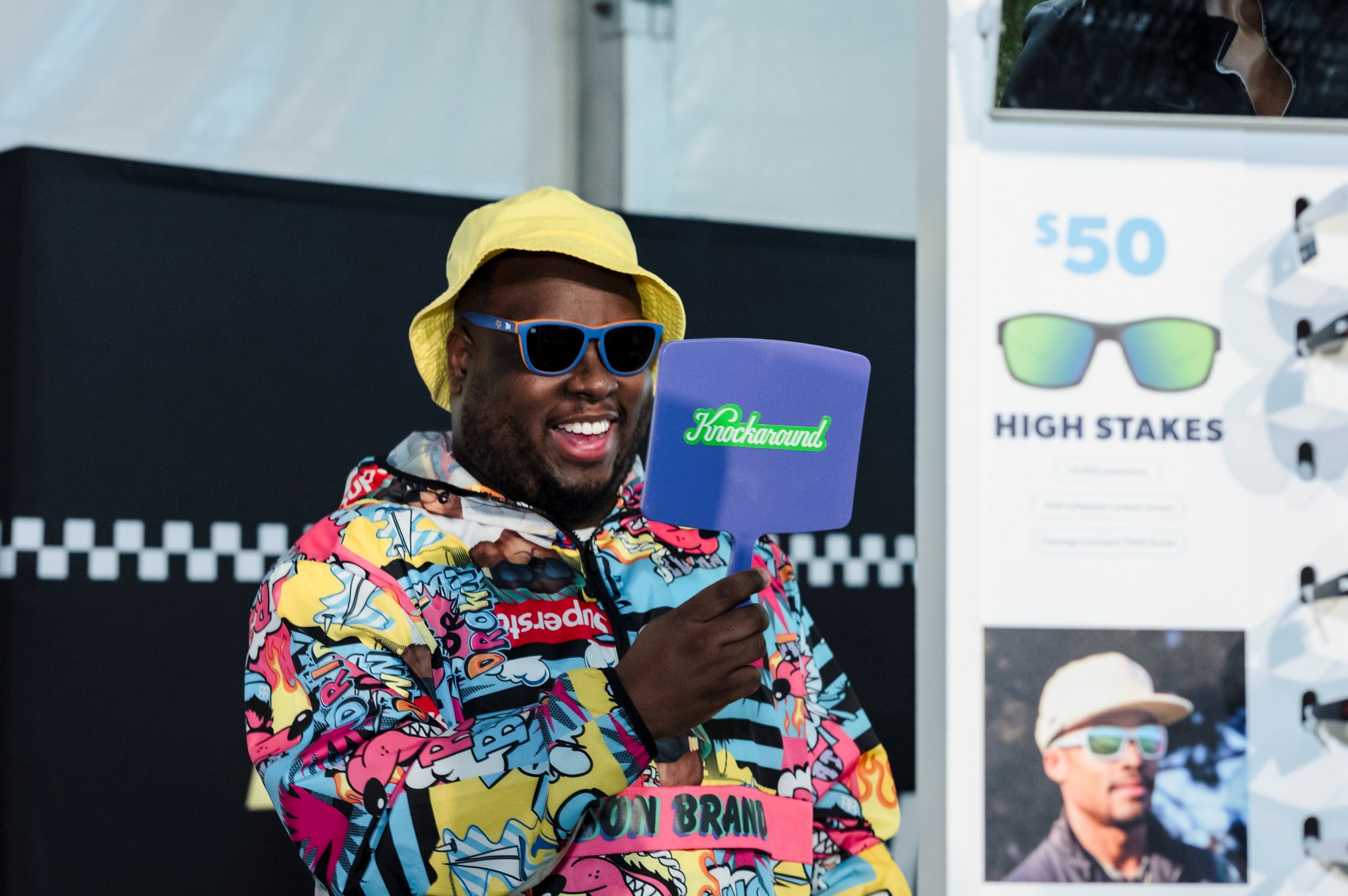 A man looks in the mirror as he tries on Knockaround sunglasses at the 2025 RBC Brooklyn Half Pre-Party