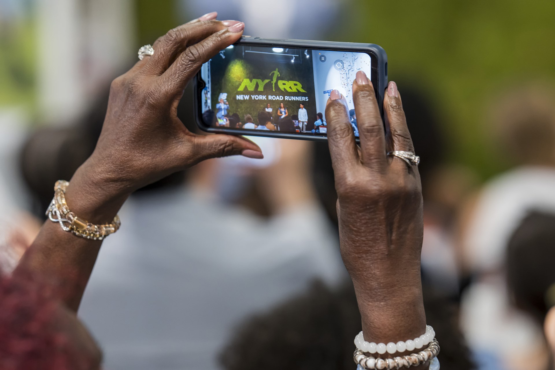Someone taking a picture on their phone of the Youth Ambassador graduation ceremony at the NYRR RUNCenter