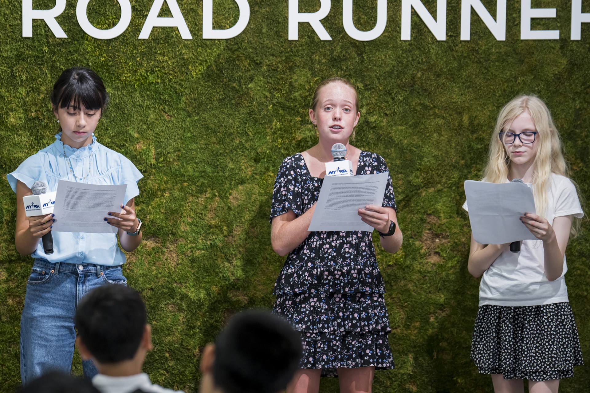 Youth ambassadors with mics and papers speaking at the youth ambassador graduation