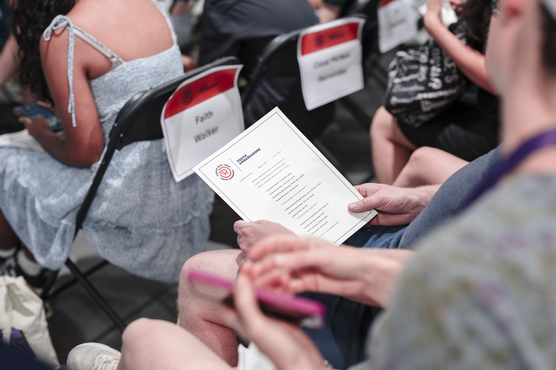 Someone holding and looking at the program for the youth ambassador graduation