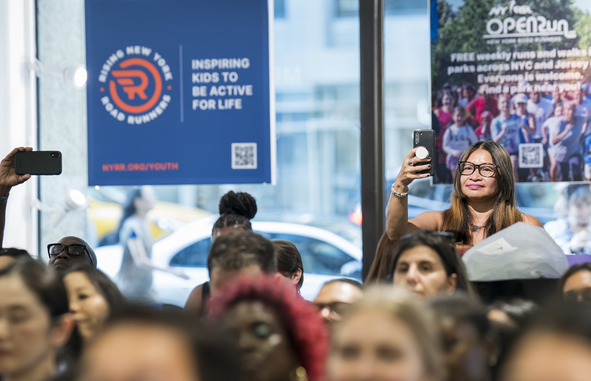 People in the audience take pictures on their phones at the youth ambassador graduation