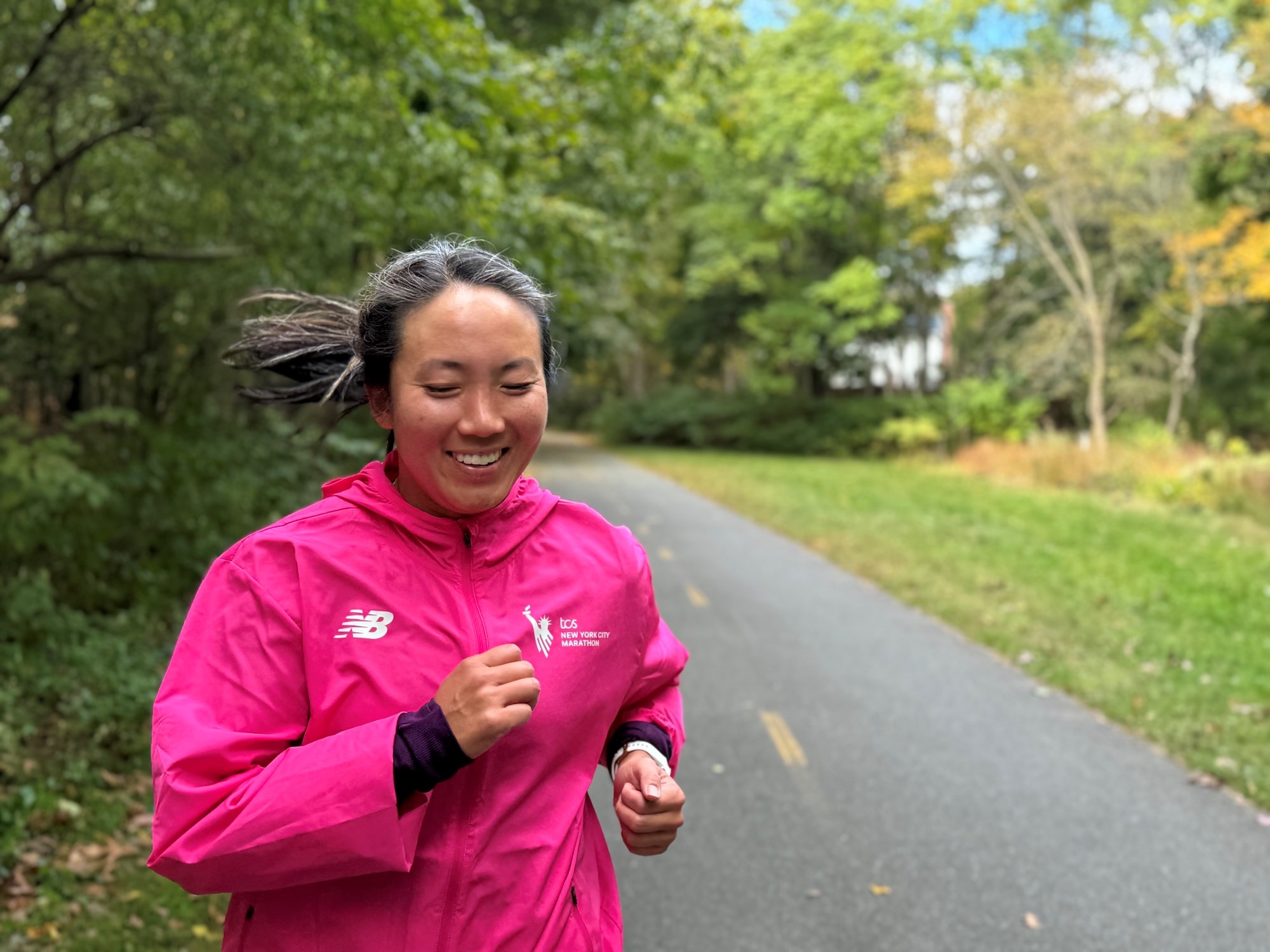 Carolyn Su running and wearing a pink TCS New York City Marathon jacket