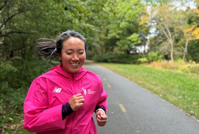 Carolyn Su running and wearing a pink TCS New York City Marathon jacket