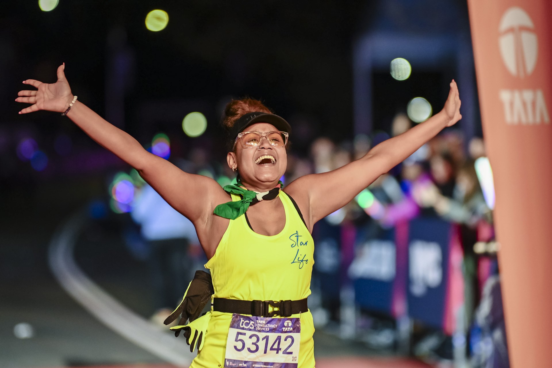 Woman runner with arms raised after finishing 2025 TCS NYC Marathon