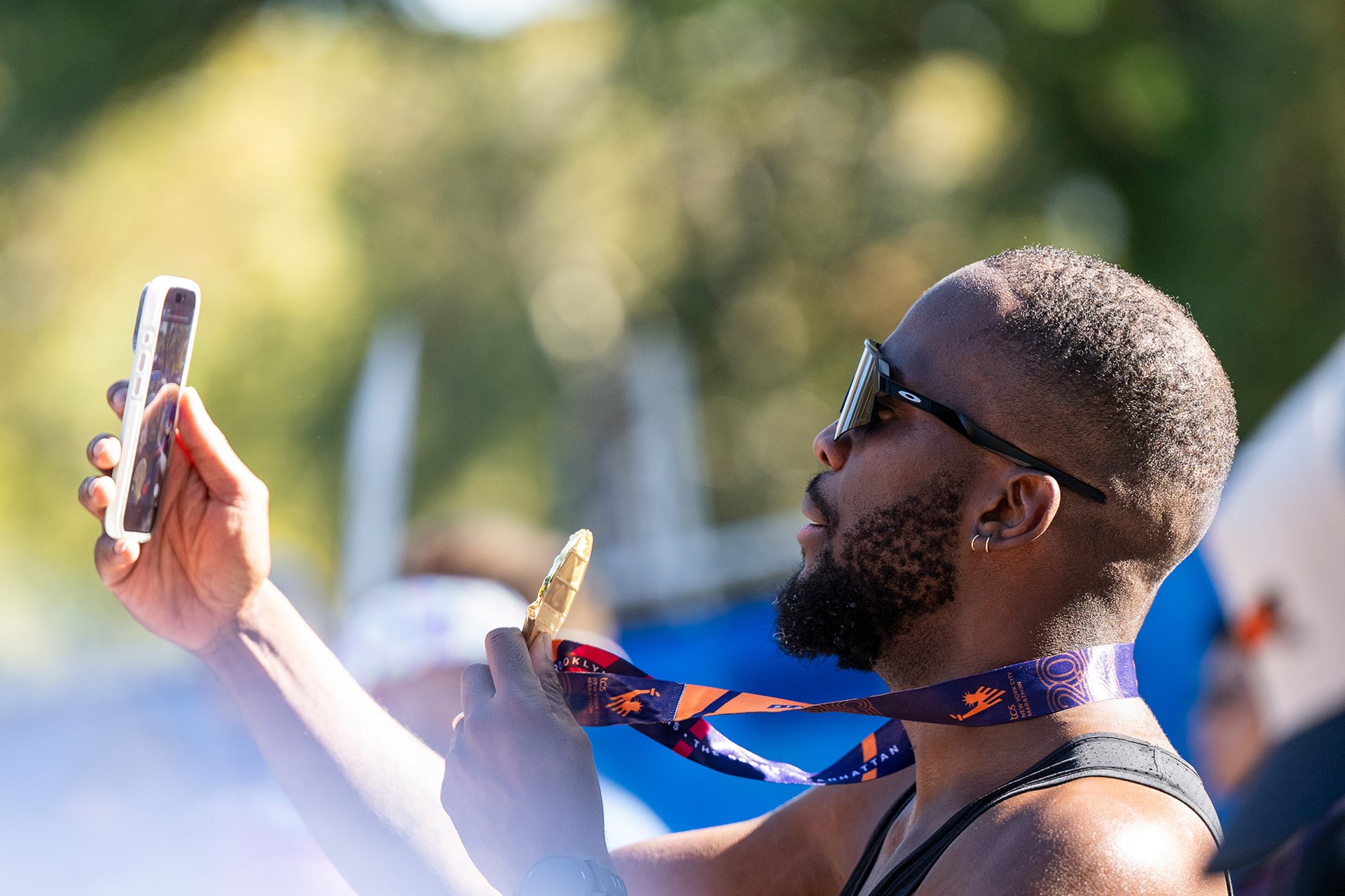 Runner with phone and medal at 2025 TCS NYC Marathon finish