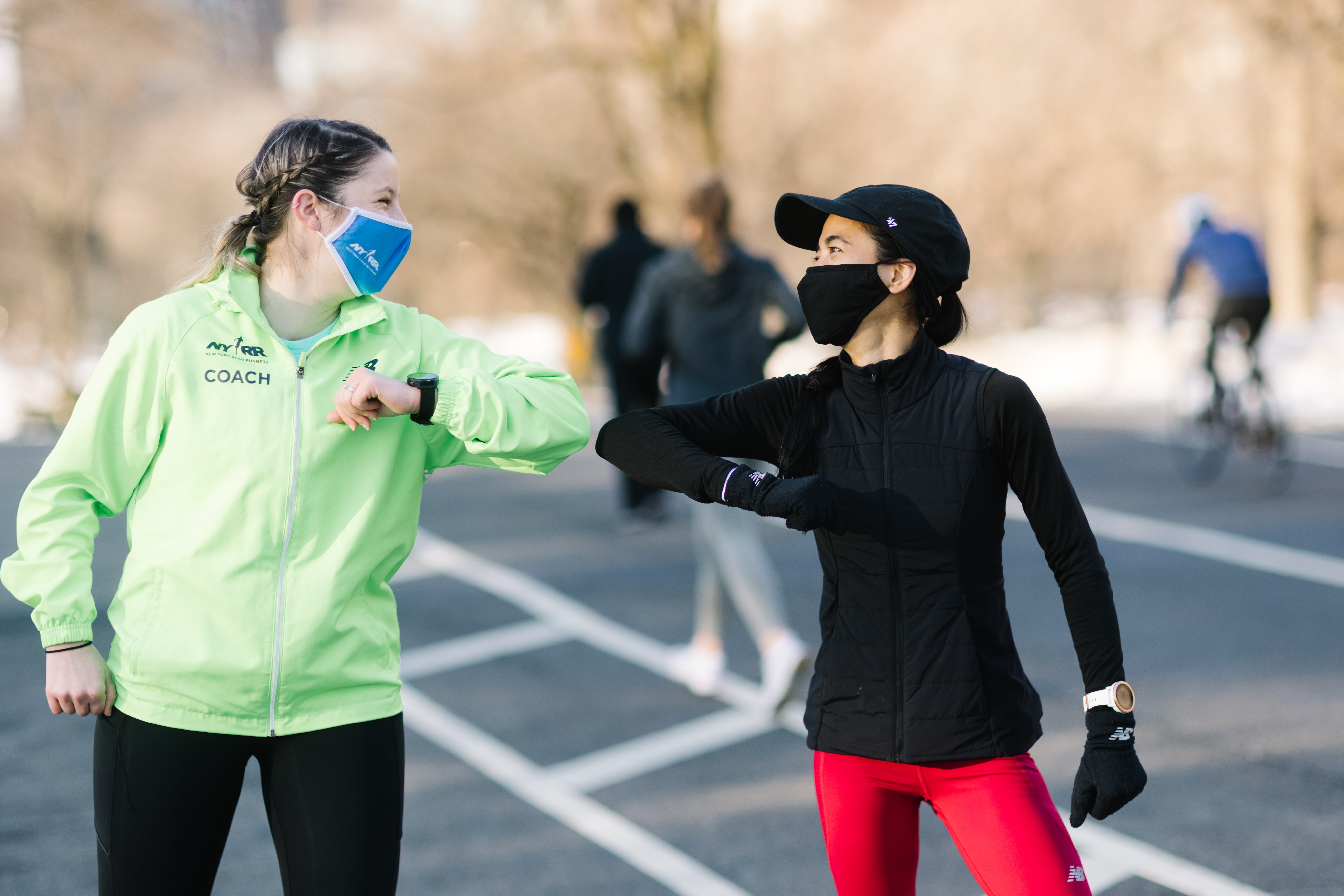 Group Training coach and runner high fiving in Central Park winter 2021 wearing masks