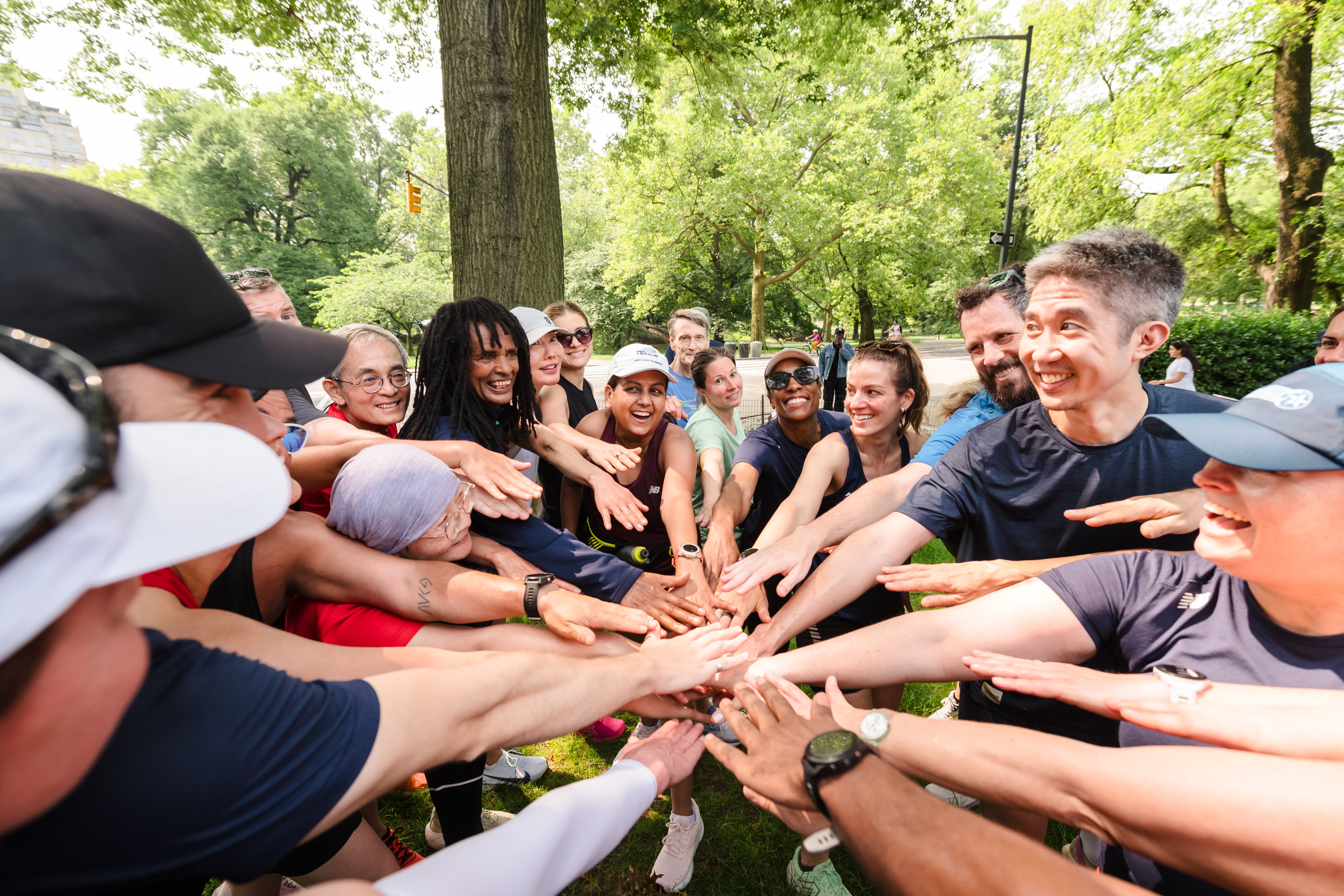 Group Training runners post-workout with hands in center of circle