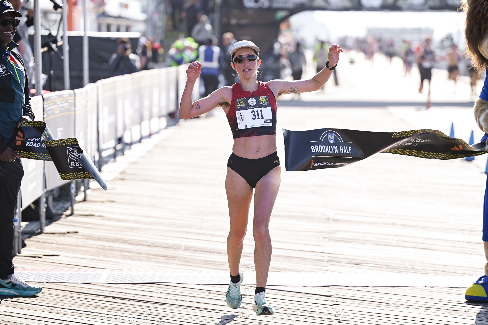 Danica Reinicke breaking the tape to win the nonbinary division of the 2026 RBC Brooklyn Half on the Coney Island boardwalk.