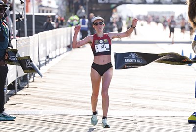 Danica Reinicke breaking the tape to win the nonbinary division of the 2026 RBC Brooklyn Half on the Coney Island boardwalk.