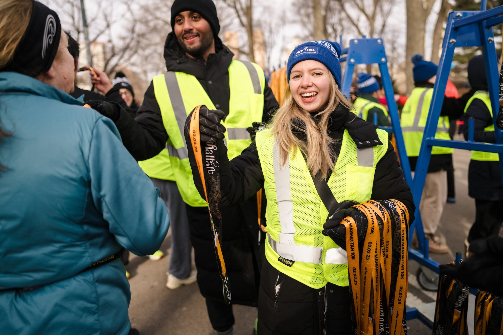 Volunteer handing runner their medal at the NYRR Manhattan 10K. 