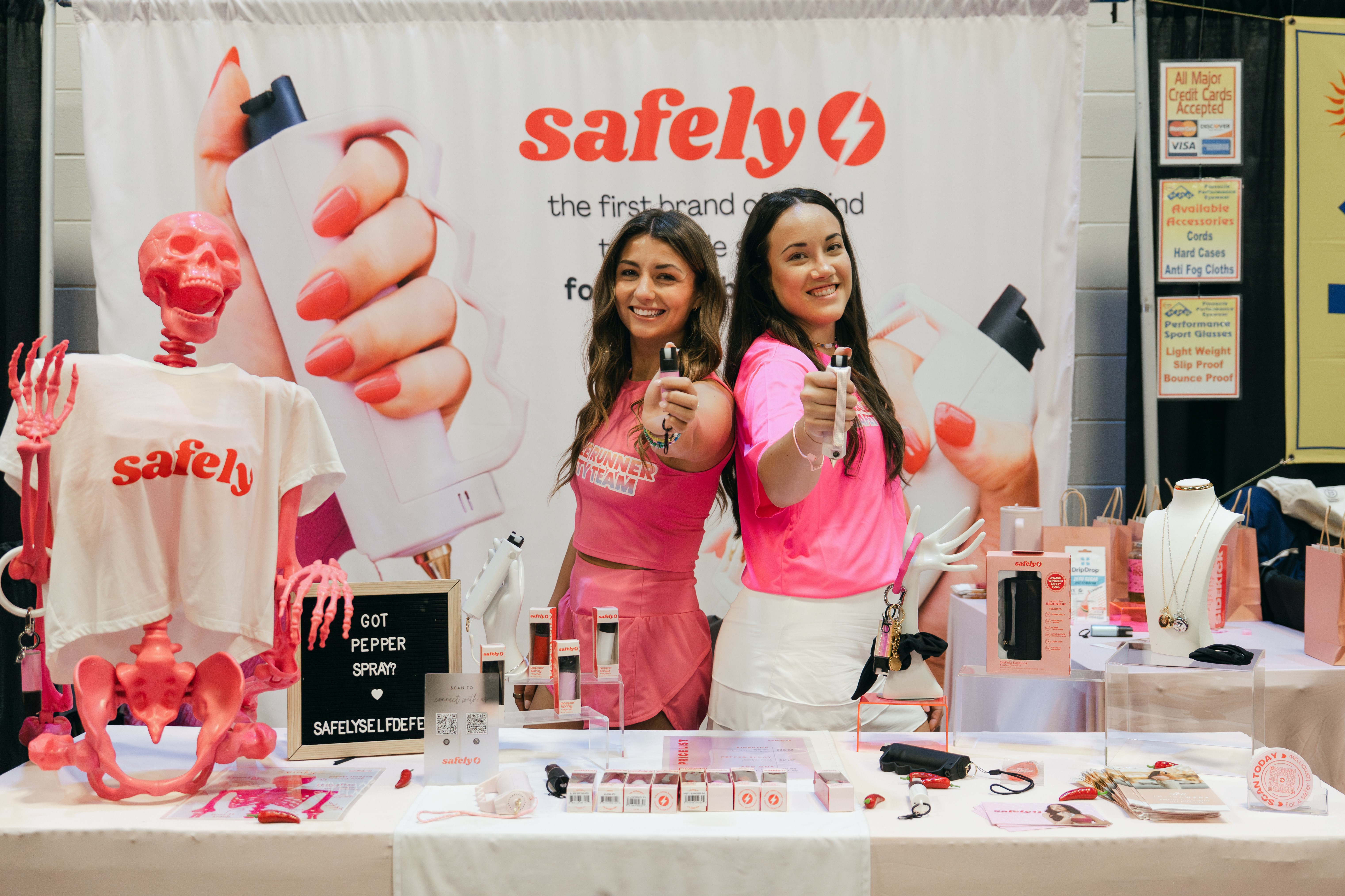 Ashley Raymond and Meagan Doyle at a Safely booth indoors with products and props.