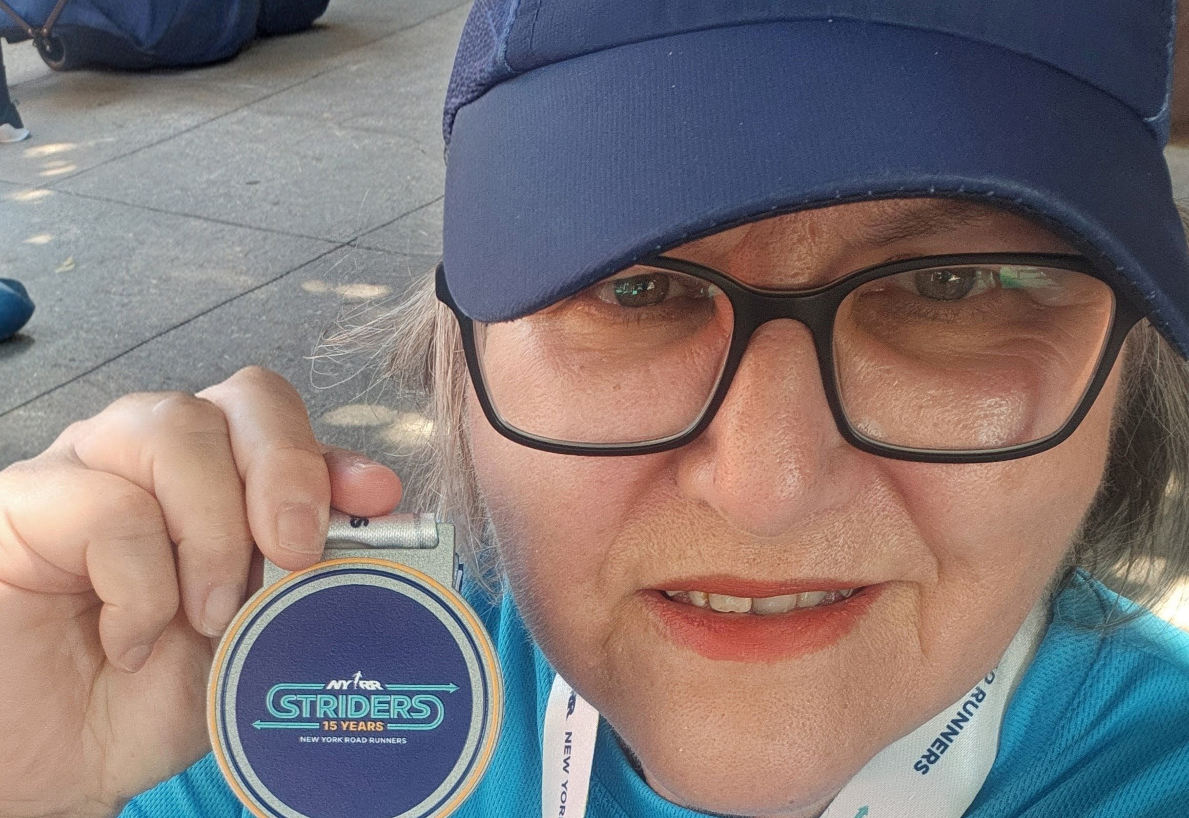 Donna Nerges with Striders medal, cap, and race bib